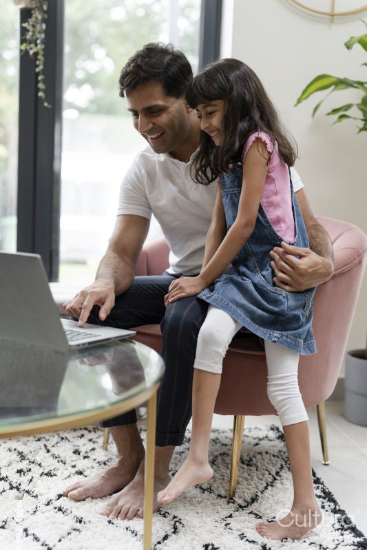 Father sitting with daughter and using laptop