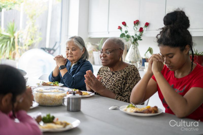 Family praying before eating dinner