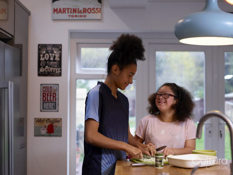 Sisters cutting vegetables in kitchen