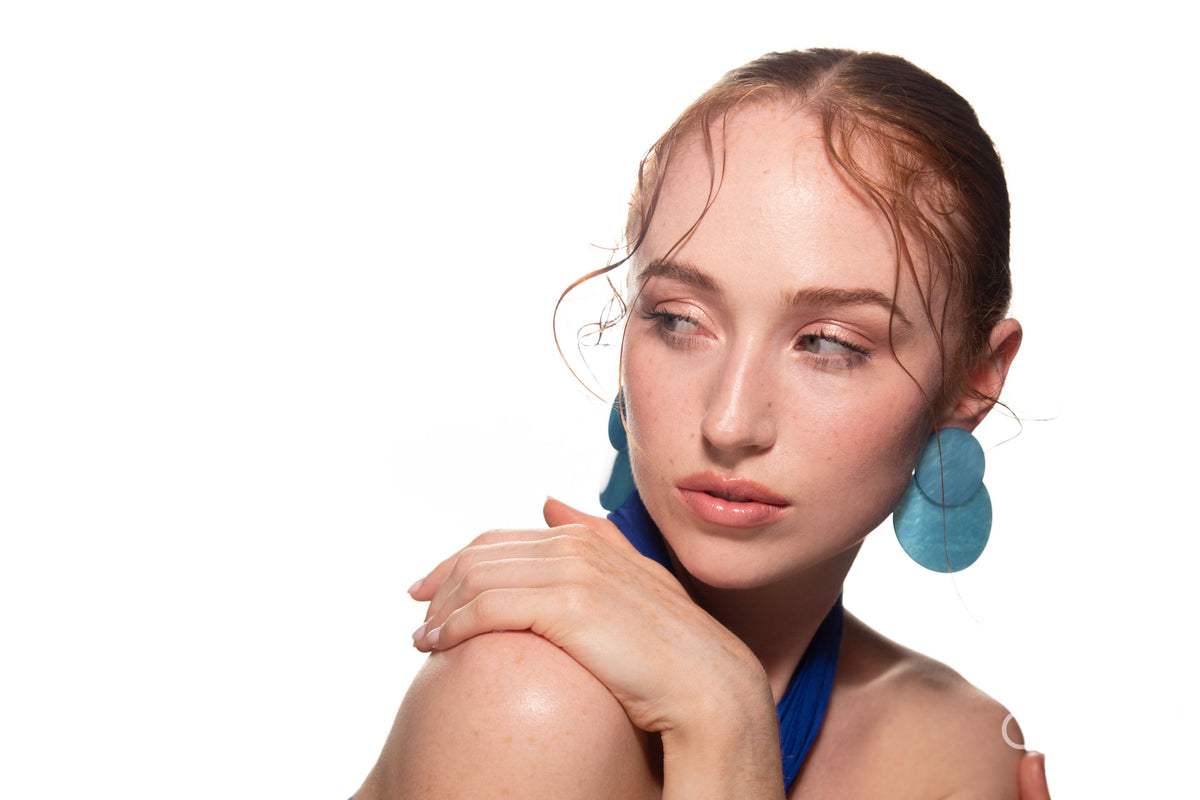 Studio portrait of a woman in a blue dress and large blue earrings