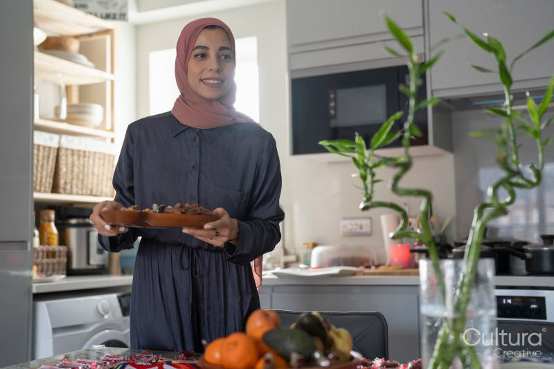 Smiling woman in hijab putting food on table