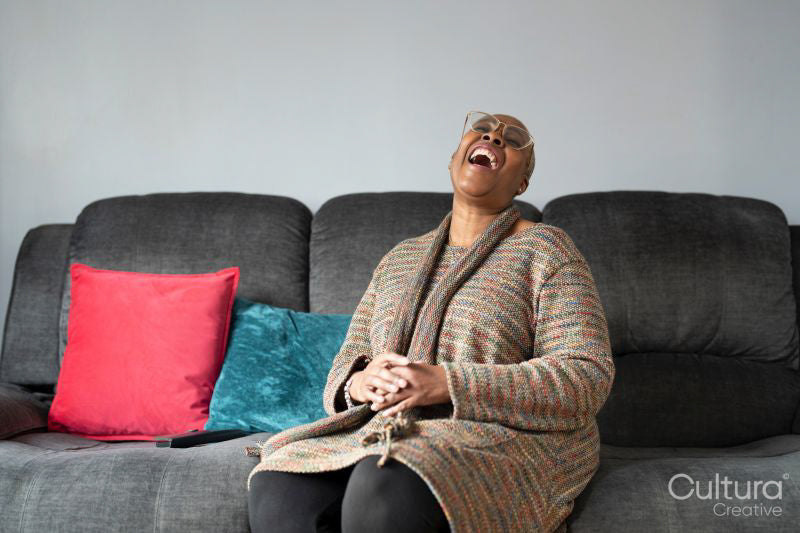 Mature woman sitting in living room and laughing