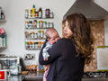 Mother holding infant daughter in kitchen