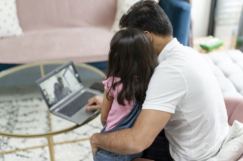 Father sitting with daughter and using laptop