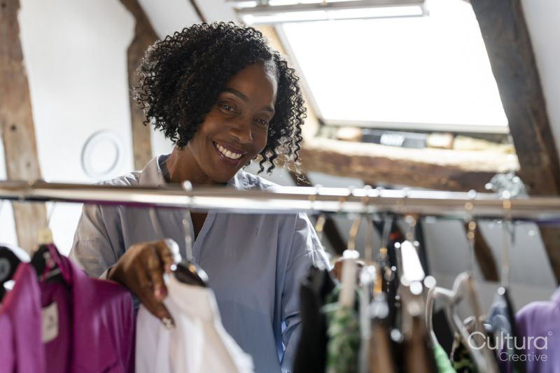 Smiling fashion designer looking at clothes