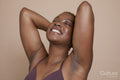 Studio portrait of smiling woman with arms raised and eyes closed