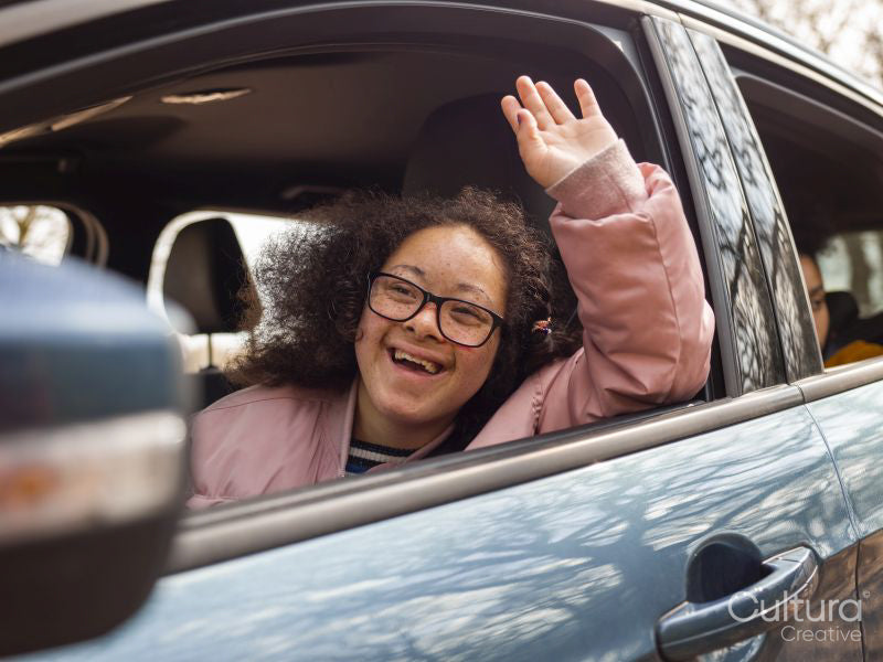 Girl waving out of car window