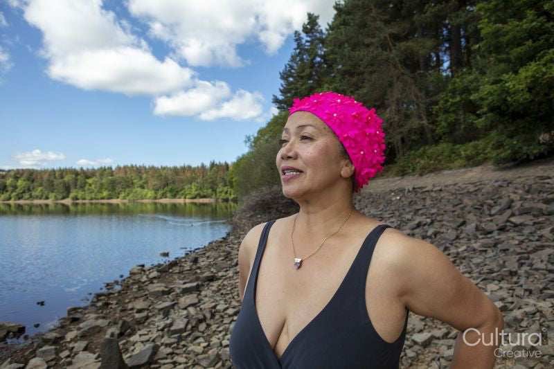 Woman in swimsuit standing on rocky lakeshore, Yorkshire, UK
