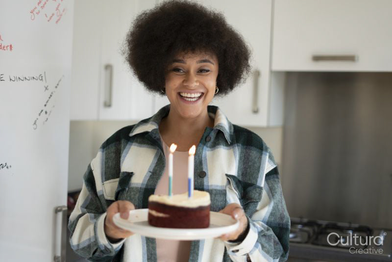 Smiling woman carrying birthday cake