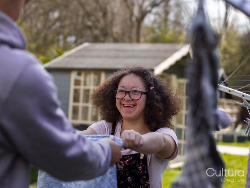 Two girls hanging laundry in backyard