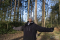 Smiling young woman with outstretched arms in forest