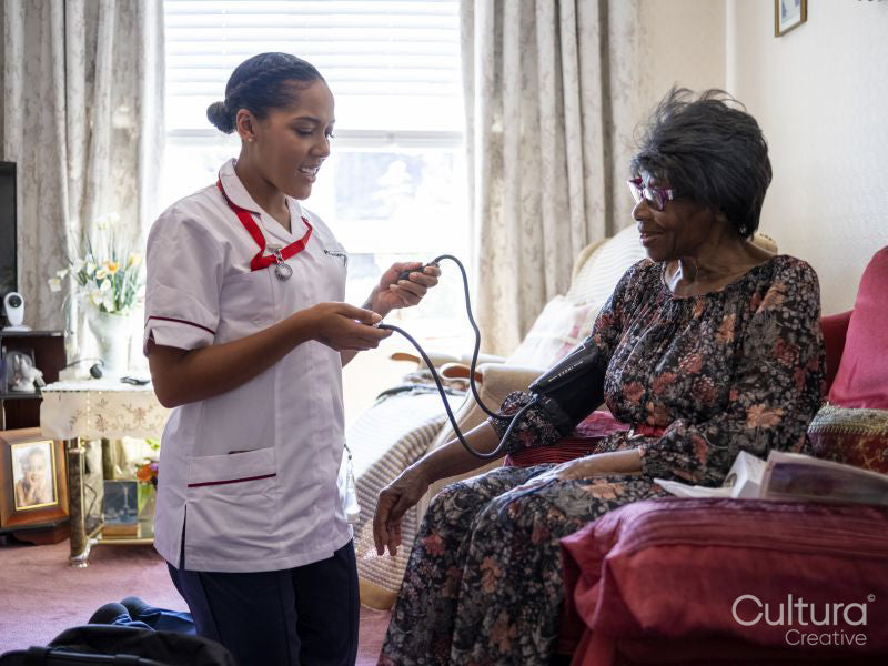 Nurse taking care of elderly woman, measuring blood pressure