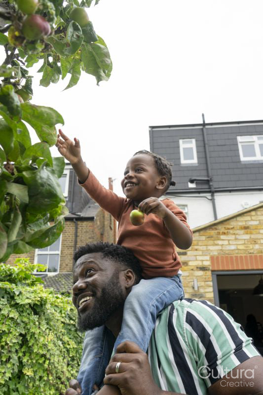 Father giving daughter piggyback ride near apple tree