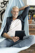 Smiling mature man using digital tablet in hammock