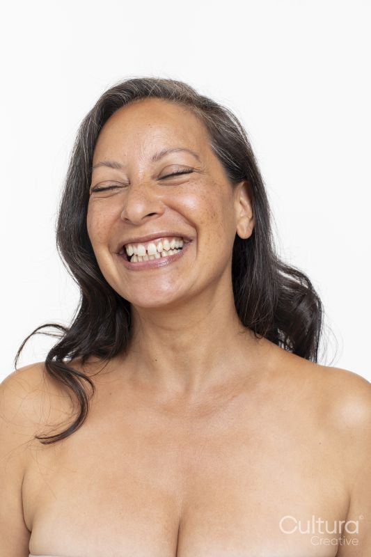 Studio portrait of smiling shirtless woman laughing