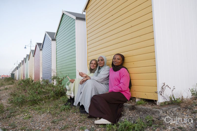 Muslim friend looking at camera while sitting by beach hut