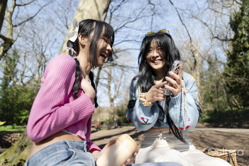 Young female friends using phone in park