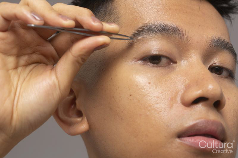 Close-up of person tweezing eyebrow