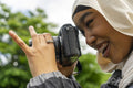 Close-up of smiling young woman wearing hijab photographing with digital camera
