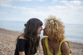 Female couple rela,ing on beach