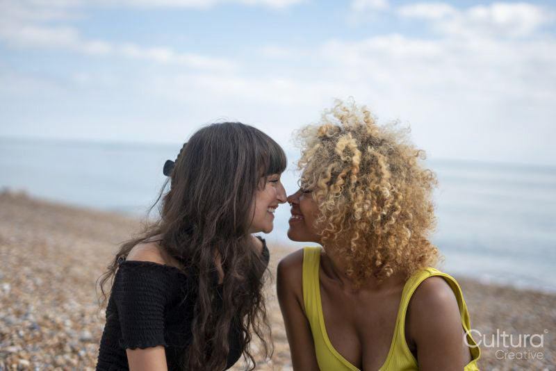 Female couple rela,ing on beach