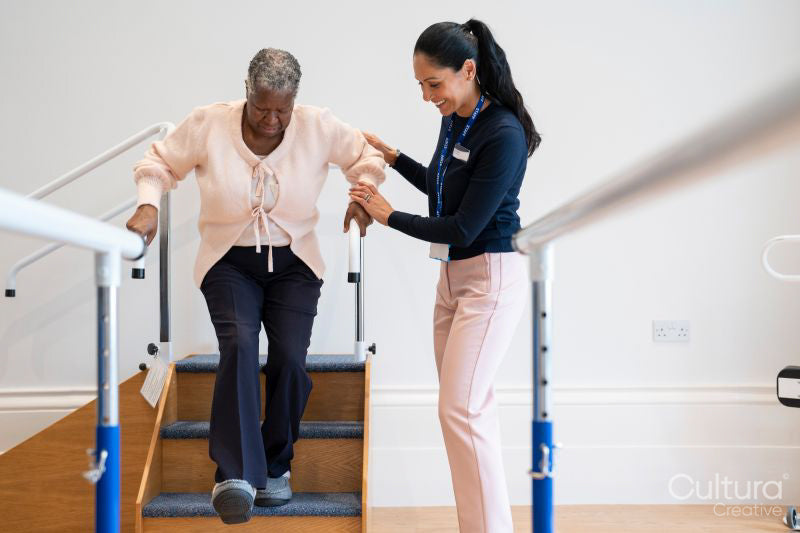 Female therapist assisting senior woman descending steps in exercise room