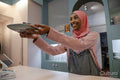 Smiling young woman in hijab working in cafe