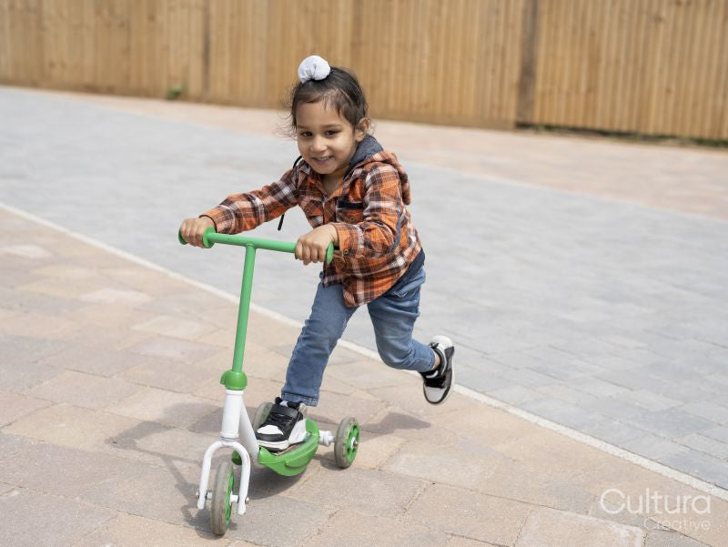 Smiling boy riding push scooter
