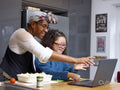 Mother with daughter with Down Syndrome looking at laptop in kitchen
