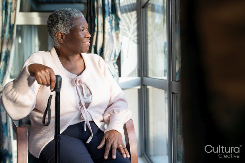 Senior woman with walking cane looking through window