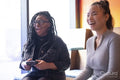 Female friends having fun while playing in video games at pub