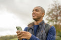 Man holding smart phone and looking away in nature