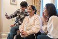 Smiling women and boy looking at smart phone together in nursing home