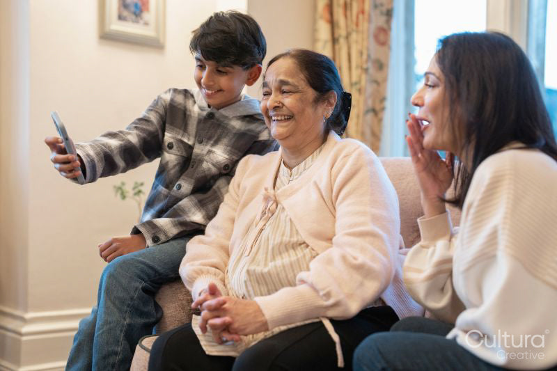 Smiling women and boy looking at smart phone together in nursing home