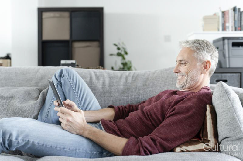Smiling mature man using digital tablet on sofa