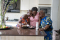 Smiling teenage girl with mother and grandmother baking muffins in kitchen