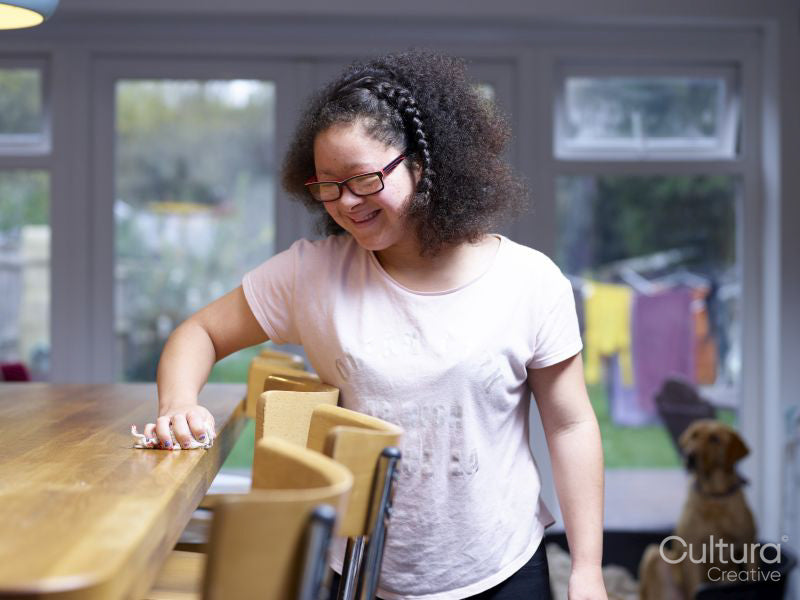 Girl with Down syndrome cleaning table