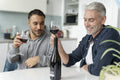 Male couple drinking red wine at home