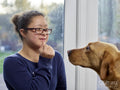 Girl with Down Syndrome playing with dog at home
