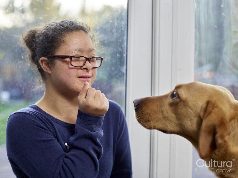 Girl with Down Syndrome playing with dog at home