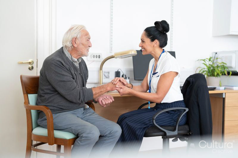 Smiling female doctor holding senior patients hand in office