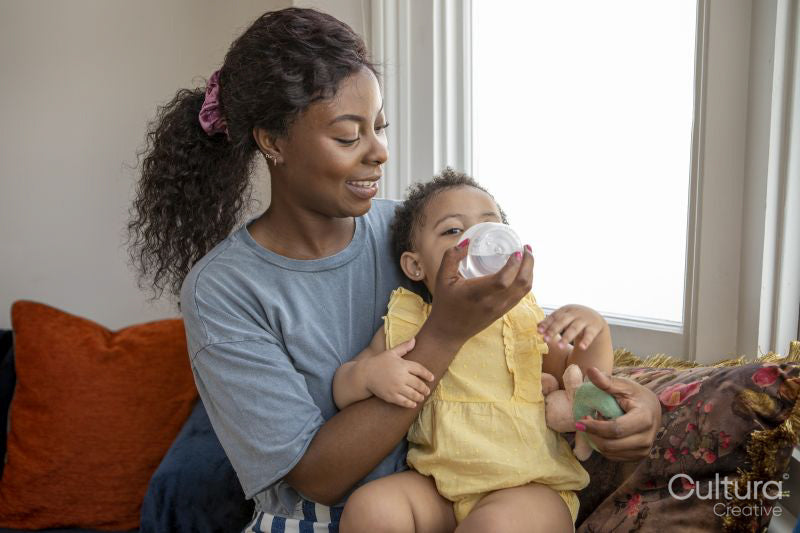 Mother giving baby daughter water to drink