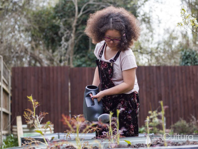 Girl watering plants in backyard