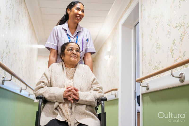 Nurse pushing senior lady sitting in wheelchair at nursing home