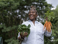 Smiling mature woman holding vegetables in allotment