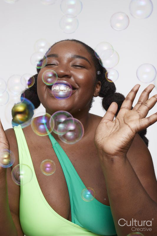 Studio shot of smiling young woman playing with soap bubbles
