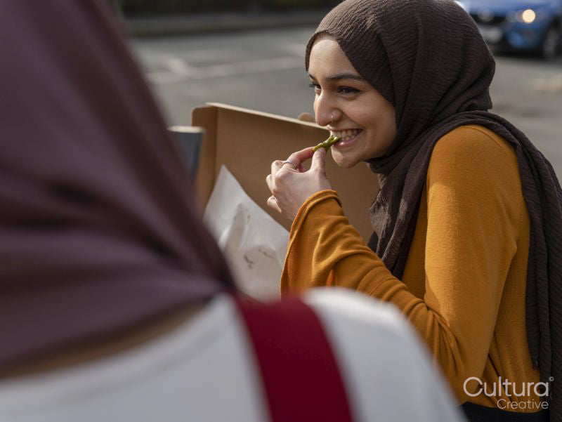 Smiling woman eating pizza in park with friend