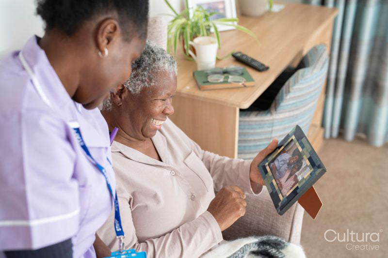 Smiling caregiver and senior woman looking at photography