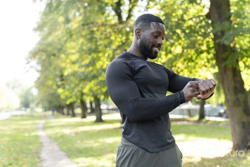 Smiling athletic man checking smart watch in park