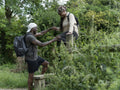 Mature couple walking over fence on hike